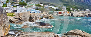 Scenic view of sea, rocks and residential buildings in Camps Bay Beach, Cape Town, South Africa. Tidal ocean waves