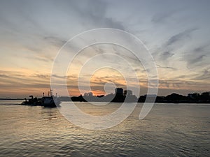 Scenic view of a ship passing through a calm sea near a port in Antwerp, Belgium during sunset