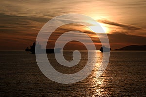 Scenic view of silhouettes of ships sailing in the sea at golden hour