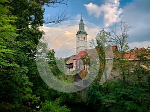 Scenic view of Skofja loka church and old houses with green foliage, Slovenia