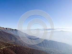 Scenic view of slopes of Vlasic mountain and Herzegovina mountains hidden in fog or smog in autumn during sunny day