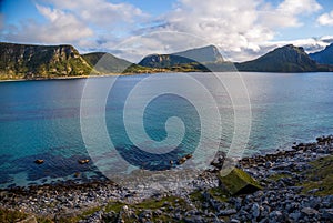 Scenic view on a small beach house, ocean and mountains against colorful sky