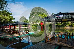 Scenic view of small tourist bamboo rafts sailing along the Yulong River among green woods and karst mountains at Yangshuo County