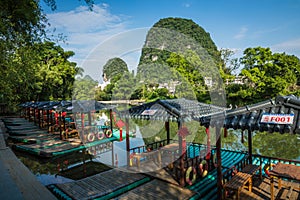 Scenic view of small tourist bamboo rafts sailing along the Yulong River among green woods and karst mountains at Yangshuo County