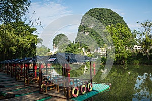 Scenic view of small tourist bamboo rafts sailing along the Yulong River among green woods and karst mountains at Yangshuo County