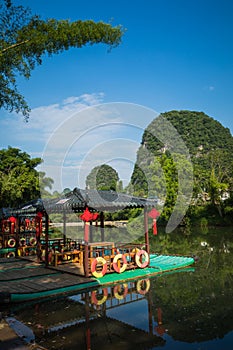 Scenic view of small tourist bamboo rafts sailing along the Yulong River among green woods and karst mountains at Yangshuo County