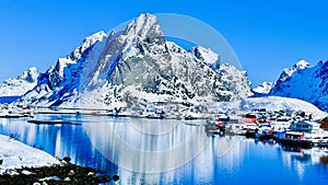 Scenic View of a snow rocky mountain and Rorbuer with reflections located along Gravdalsbukta. Lofoten Islands Norway Aurora photo