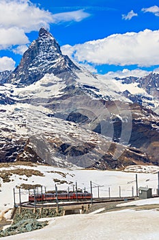 Scenic view on snowy Matterhorn mountain peak in the Swiss Alps with cogwheel train of Gornergrat railway close to Zermatt,