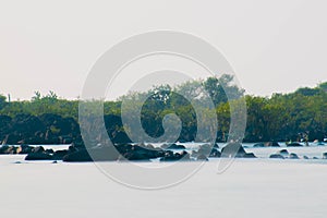 scenic view of sooth silky sea water with boulders and green mangroves