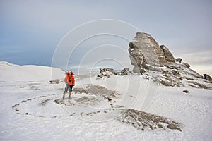 Scenic view of the Sphinx of Romania in the Bucegi mounatins during winter with a young gril climber. photo