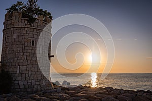 Scenic view of a stone tower on the beach against the sea at sunset