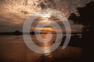 Scenic view of the strong sunrise with silver lining and clouds on the orange sky