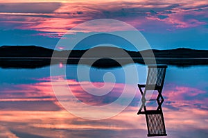 Scenic view of sunset with chair in calm water