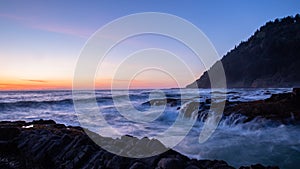 Scenic view of a sunset over ocean. Crushing waves enter into a chasm at Cape Perpetual, Oregon Coast