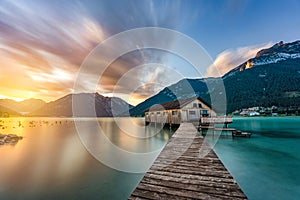 Scenic view of a sunset sky over the wooden pier to the house in a water of sea