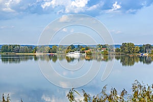 Scenic view to Altmuehl river in Bavaria with tourist ship on pier and reflection of coastline