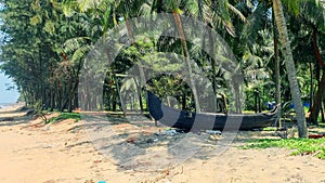 Scenic view to tropical beach  with  traditional fishing boat and beach huts on the coconut trees background in Kerala, South