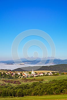 Scénický pohled na tradiční vesnici, hrad, louky a hory