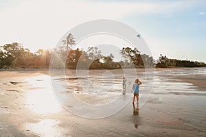 Scenic view of two white Caucasian kids with blond hair playing with a kite