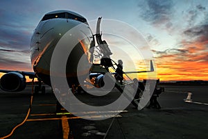 Scenic view of unrecognizable passengers silhouette boarding on airplane at sunset