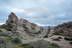 Scenic view of Vasquez Rocks Park in Agua Dulce, California with bushes against a clouded sky photo