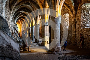 Scenic view of vaulted gothic dungeons and tourists looking at an information board in the underground of Chillon castle