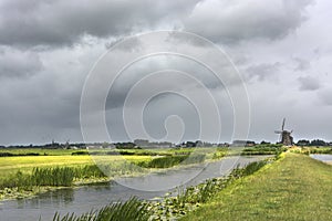 Scenic view with water, grass, thunderclouds and windmill ithe environment of Zwammerdam. the Netherlands. Zwammerdam is a villag