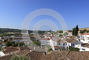 Scenic view of white houses red tiled roofs, and castle from wall of fortress. Beautiful old town with medieval. Obidos village,