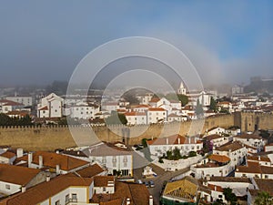 Scenic view of white houses red tiled roofs, and castle from wall of fortress with clouds. Obidos village, Portugal.