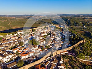 Scenic view of white houses red tiled roofs, and castle from wall of fortress. Obidos village, Portugal.