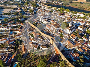 Scenic view of white houses red tiled roofs, and castle from wall of fortress. Obidos village, Portugal.