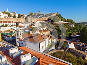 Scenic view of white houses red tiled roofs, and castle from wall of fortress. Obidos village, Portugal.