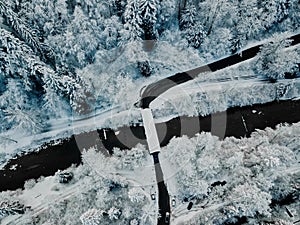 Scenic view of a winter road winding through a forest of frost-covered trees.