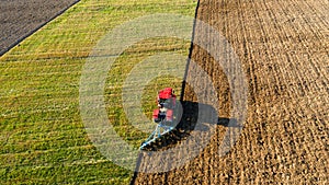 Scenic view of working tractor in the field agricultural field on a summer farm in the evening