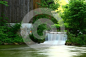 Scenic waterfall flowing into a lush creek, surrounded by greenery