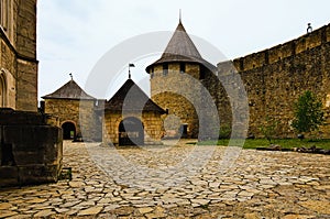 Scenic wide-angle view of courtyard with ancient stone buildings in the medieval castle. High stone wall with tower