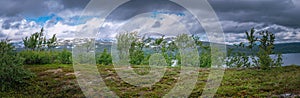 Scenic wide panorama on high altitude Norwegian Mountains range terrain with mountains, clouds and lake at horizon line. Hiking
