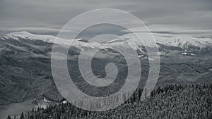 Scenic winter landscape in the mountains with clouds above and below and woods covered in snow