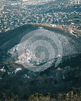 A scenic winter landscape of rolling hills and a small residential area in Normafa, Hungary