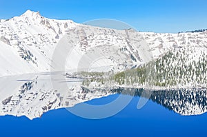 Scenic winter mirror reflection of snowcap mountain and Wizard Island on Crater Lake