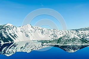 Scenic winter mirror reflection of snowcap mountain and Wizard Island on Crater Lake