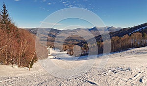 Scenic winter scene featuring a ski slope with fresh snow blanketing and majestic mountains