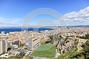 A scenics aerial view of the city of Marseille, bouches-du-rhone, France with a grass football field under a majestic blue sky