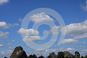 Scenics of the blue skies with clouds against stone mountain on bright day.