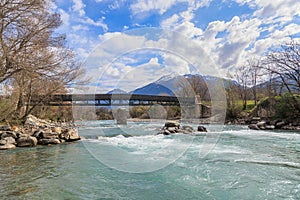 A scenics view of the Durance river flowing under a wooden walking bridge under a majestic blue sky