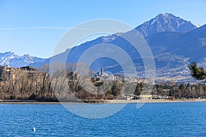 A scenics view of the Embrun, France lake with snowy mountains range in the background under a majestic blue sky