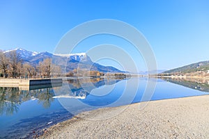 A scenics view of the Embrun, France lake with snowy mountains range in the background under a majestic blue sky