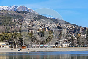 A scenics view of the Embrun, France lake with snowy mountains range in the background under a majestic blue sky