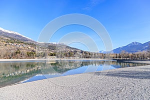 A scenics view of the Embrun, France lake with snowy mountains range in the background under a majestic blue sky