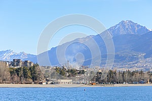 A scenics view of the Embrun, France lake with snowy mountains range in the background under a majestic blue sky